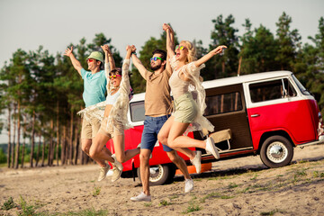 Full size photo of group overjoyed buddies hold hands jumping enjoy free time rejoice sand beach outdoors