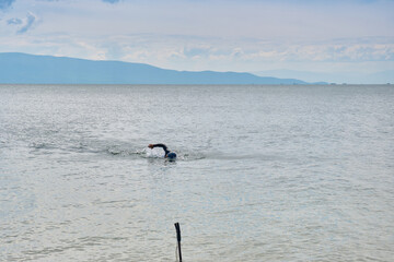 A man in a wetsuit trains in open water on Lake Baikal in the Chivyrkuysky Bay of the Republic of Buryatia.