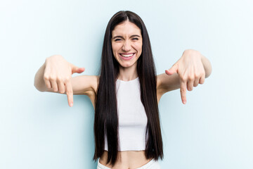 Young caucasian woman isolated on blue background points down with fingers, positive feeling.