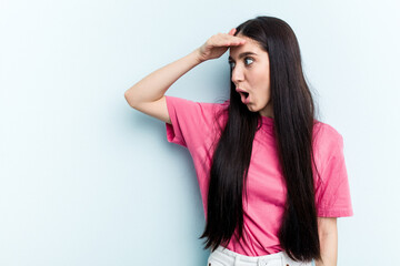 Naklejka premium Young caucasian woman isolated on blue background looking far away keeping hand on forehead.
