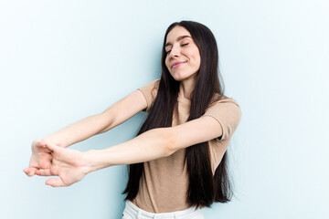 Young caucasian woman isolated on blue background stretching arms, relaxed position.