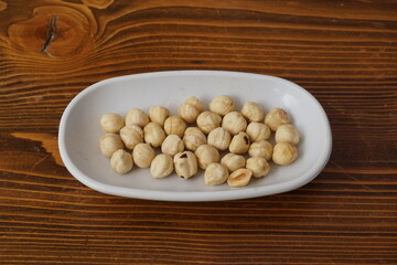 some roasted hazelnuts on a wooden floor in a white plate