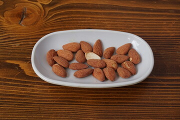 some roasted snack almonds on a wooden floor in a white plate