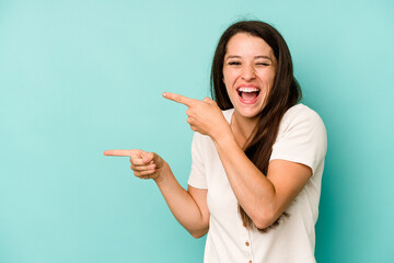 Young caucasian woman isolated on blue background excited pointing with forefingers away.