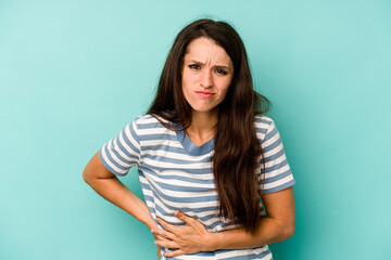 Young caucasian woman isolated on blue background having a liver pain, stomach ache.