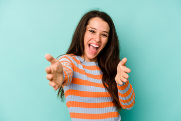 Young caucasian woman isolated on blue background feels confident giving a hug to the camera.