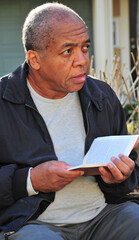 African american man reading outdoors.