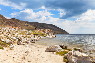 Baikal Lake. Sandy beach and rocky shore in the shallow bay of Ust-Anga. Tourists travel along the coast and explore the surroundings