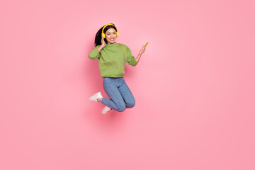 Fototapeta na wymiar Full length photo of nice millennial lady jump listen music wear pullover jeans sneakers isolated on pink background