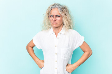 Middle age caucasian woman isolated on blue background frowning face in displeasure, keeps arms folded.