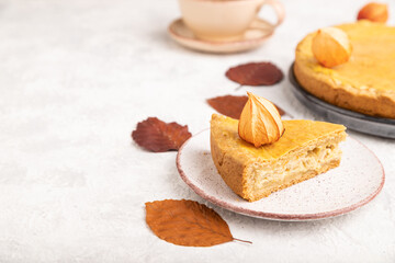 Autumn onion pie decorated with leaves and cup of coffee on gray concrete background. Side view, selective focus.