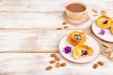 Obraz na płótnie Canvas Small cheesecakes with jam and almonds with cup of coffee on a white wooden background. Side view, copy space.