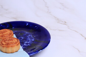 Chinese moon cake on a white marble background. Asian traditional mid-autumn festival. Translation of hieroglyphs: mango, pomegranate and lotus.