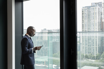 African American businessman using smartphone with view of city skyline