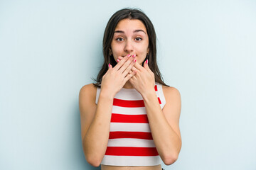 Young caucasian woman isolated on blue background shocked covering mouth with hands.