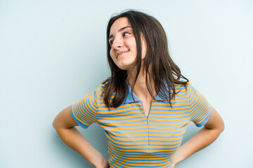 Young caucasian woman isolated on blue background laughs happily and has fun keeping hands on...