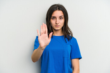 Young caucasian woman isolated on white background standing with outstretched hand showing stop sign, preventing you.