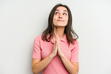 Obraz premium Young caucasian woman isolated on white background holding hands in pray near mouth, feels confident.