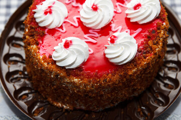 Cake Lady Cherry, a delicious, sweet confection with red, pink, white glaze, crumbs and cherries lies on table. Top view