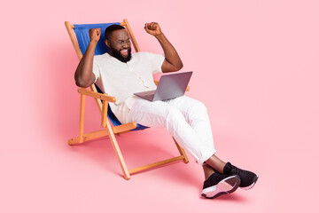 Full size photo of delighted person sit chair raise fists celebrate isolated on pink color...