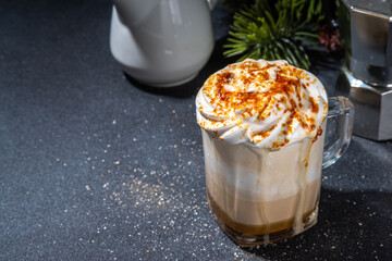 Salted Caramel Brulee Latte. Sweet creamy hot coffe latte drink with whipped cream and caramelized sugar, on dark table background. Autumn winter warm dairy milk coffee beverage