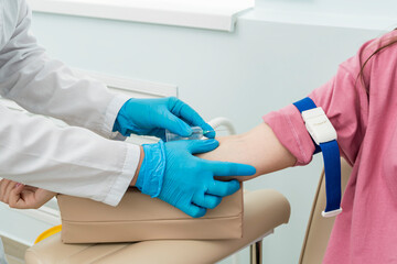 Obraz premium Cropped hands of nurse in blue gloves perform blood sampling procedure for analysis from patient's right hand