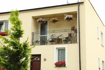 Fototapeta na wymiar Stylish balcony decorated with beautiful potted flowers and chairs