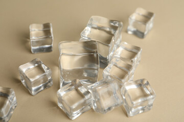 Crystal clear ice cubes on beige background, closeup