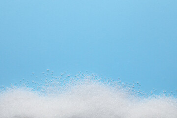 Granulated sugar on light blue background, top view. Space for text