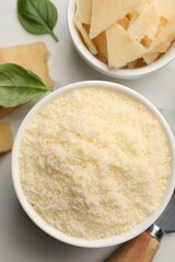 Bowl with grated parmesan cheese on white table, flat lay