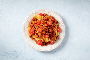 Spaghetti bolognese pasta with cherry tomatoes, overhead flat lay shot