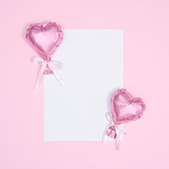 Copy space white paper with pink balloons heart on pastel pink background. Flat lay VAlentine's day concept