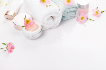 Beauty and spa concept. Towel and skin care cosmetics with rose hips on a white background. Flat lay.