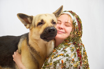Beautiful smiling girl in stylized slavic red and white national costume and big dog on white background. Funny woman and model posing with big shepherd in studio