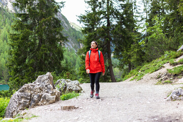 Fototapeta premium Spiritually strong woman hiking alone in the mountains in red raincoat