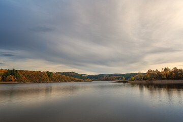 Blick auf den Biggesee und die Wälder und Berge mit herbstlichen Farben und Wolken am Himmel