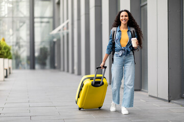 Cheerful pretty young woman having journey abroad, full length