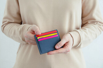 Credit bank cards in a gray business card holder in hands of a caucasian woman. White background.