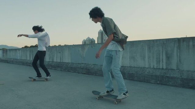Boys riding skate on urban street, teenagers lifestyle. Two friends skateboarding in city, tracking shot, slow motion. Kids friendship, freedom, youth concept