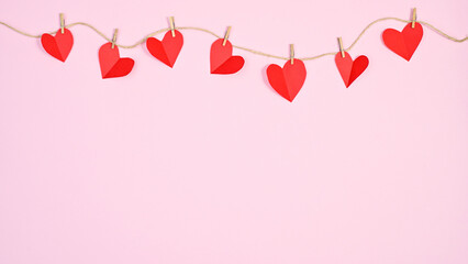 Creative hearts hanged on rope on pastel pink copy space background. Creative Valentine's day concept