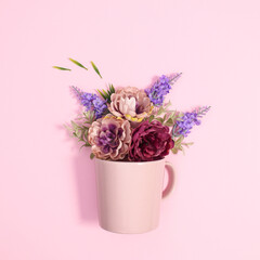 Pastel pink ceramic cup with spring flowers in it. Flat lay creative concept