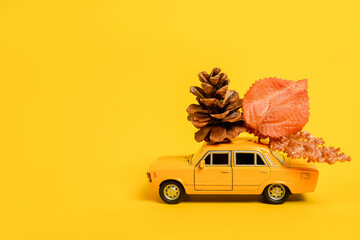 Gele speelgoedauto met herfstsamenstelling op gele achtergrond. kopieer ruimte, reisconcept. Taxi