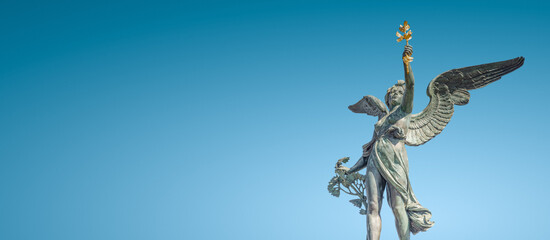 Banner with Statue of beautiful angel  at the top of column on the Cechuv Most Bridge in Prague,...
