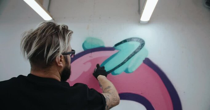 Graffiti artist draws on the wall of a contemporary art gallery. handheld camera