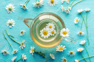Chamomile tea in a teapot with loose flowers, herbal medicine treatment, overhead flat lay shot on...