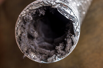A dirty laundry flexible aluminum dryer vent duct ductwork filled with lint, dust and dirt - Powered by Adobe