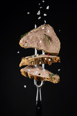 Steak from baked meat with spices sprinkled with sea salt on a black background. Menu idea for a restaurant or hotel