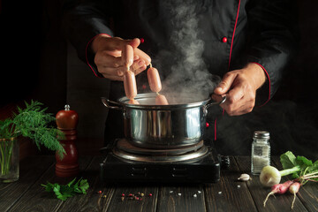 Professional chef prepares delicious meat sausages in a saucepan. Menu idea for a hotel or restaurant