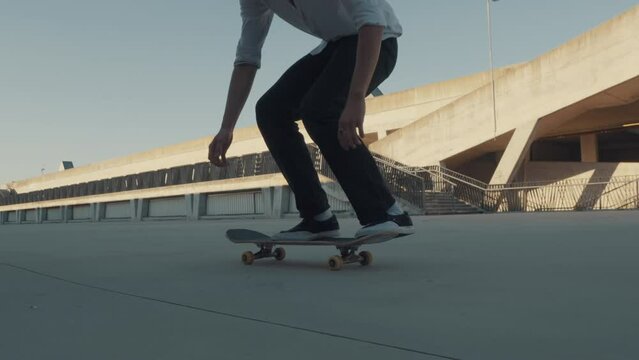 Boy riding skateboard at skate park, slow motion medium tracking shot. Outdoor freestyle skaters training. Teen lifestyle, kid pastime activity, youth concept