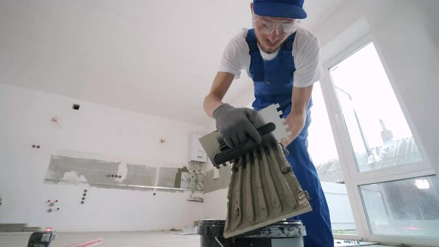 Installing ceramic floor tiles - measuring and cutting the pieces. Construction, renovation, repair apartment. Cuts tile. Tile cutting